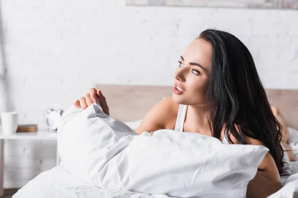 Jovem morena mulher na cama olhando para longe — Fotografia de Stock