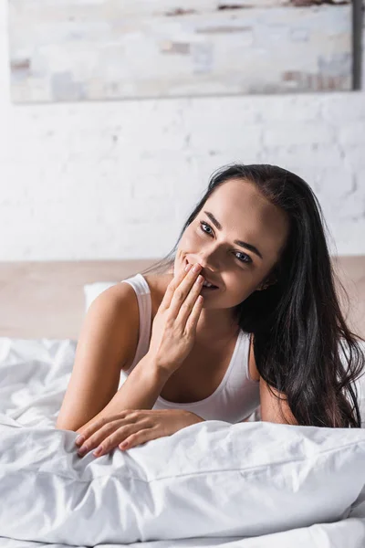 Lächelnde junge brünette Frau im Bett — Stockfoto