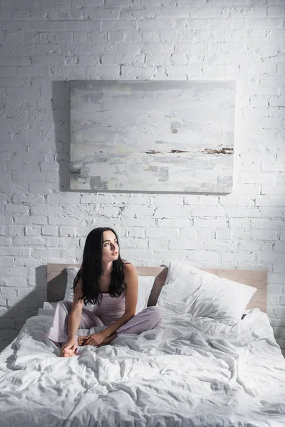 Junge brünette Frau sitzt morgens im Bett — Stockfoto