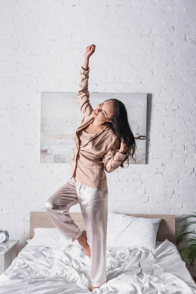 Joven morena bailando en la cama por la mañana - foto de stock