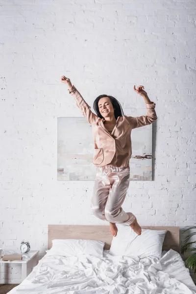 Jeune femme brune sautant au lit le matin — Photo de stock