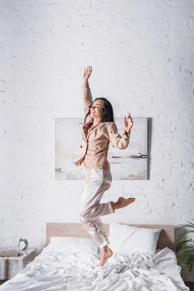 Young brunette woman jumping in bed at morning — Stock Photo