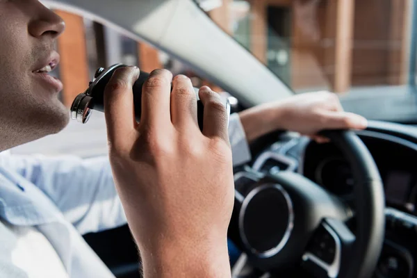 Cropped view of man drinking alcohol from flask while driving car, blurred background — Stock Photo