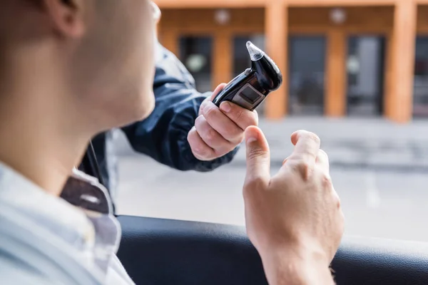 Ausgeschnittene Ansicht eines Polizisten, der dem Fahrer im Auto einen Atemalkoholtest gibt, verschwommener Vordergrund — Stockfoto