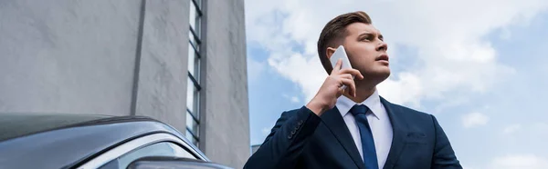 Jeune homme d'affaires détournant les yeux tout en parlant sur smartphone à l'extérieur, bannière — Photo de stock