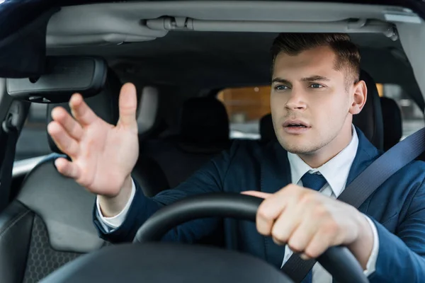 Empresario apuntando con la mano mientras conduce auto en primer plano borroso - foto de stock