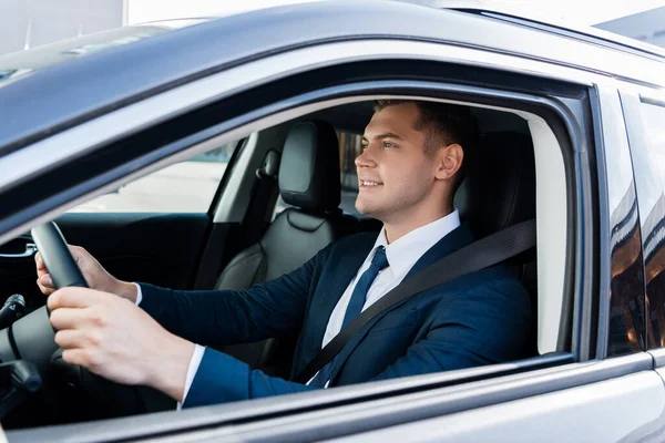 Empresário sorridente dirigindo carro em primeiro plano desfocado — Fotografia de Stock