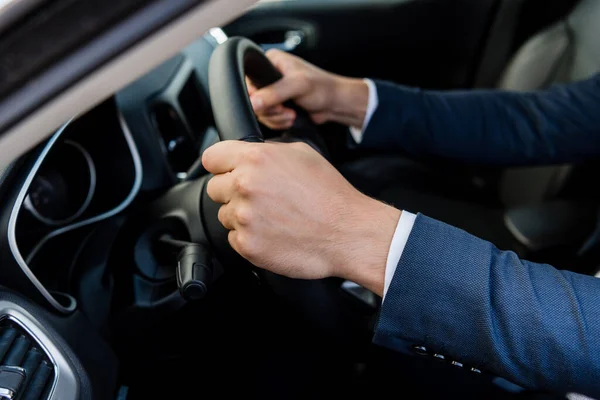 Vista cortada do homem de terno carro de condução no fundo embaçado — Fotografia de Stock