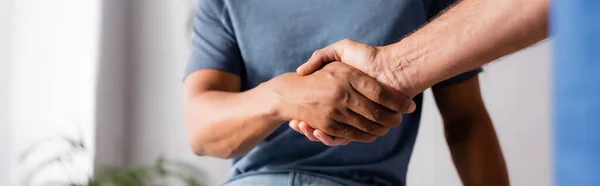 Abgeschnittene Ansicht multikultureller Männer beim Händeschütteln in der Klinik, Banner — Stockfoto