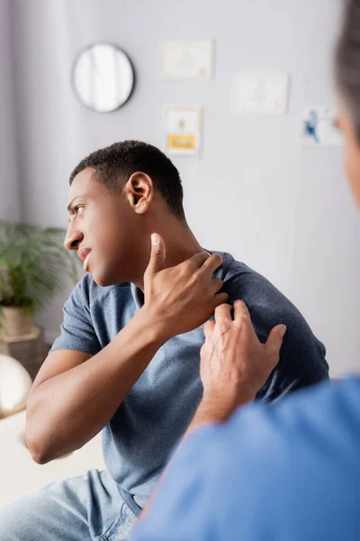 Doctor borroso tocando herido africano americano paciente — Stock Photo