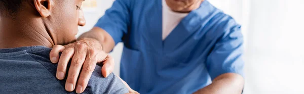 Chiropractor working with injured arm of african american patient, banner — Stock Photo