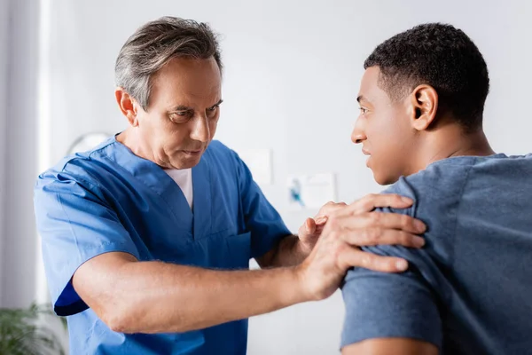 Chiropractor working with injured arm of african american patient — Stock Photo