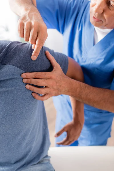 Vue recadrée du thérapeute examinant le patient afro-américain blessé en clinique — Photo de stock