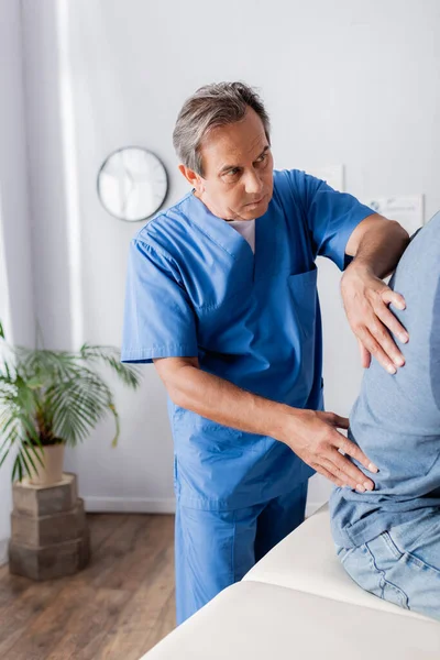 Mature chiropractor working with african american patient on massage table — Stock Photo