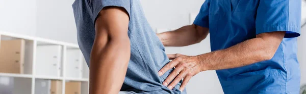 Cropped view of mature chiropractor working with african american man, banner — Stock Photo