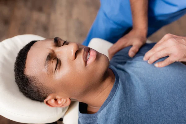 Masseur massaging african american patient on massage table — Stock Photo