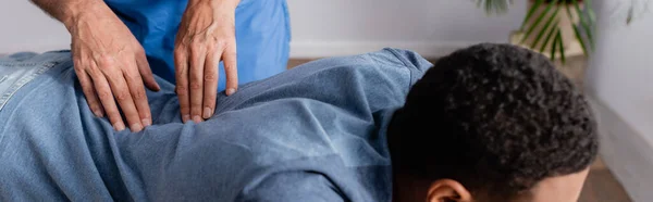 Partial view of chiropractor working with young african american patient in clinic, banner — Stock Photo