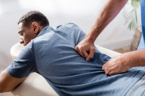 Chiropraktiker arbeitet mit jungen und verletzten afrikanisch-amerikanischen Patienten auf Massagetisch in Klinik — Stockfoto