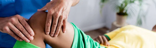 Cropped view of masseur massaging knee of african american sportsman, banner — Stock Photo
