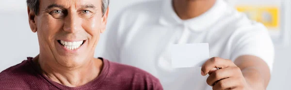 Homem feliz sorrindo perto de Africano americano terapeuta segurando cartão em branco, banner — Fotografia de Stock