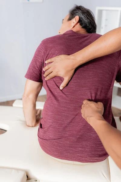 Quiroprático afro-americano trabalhando com costas de homem de meia-idade na mesa de massagem — Fotografia de Stock