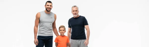 Enfant heureux avec grand-père et père en vêtements de sport souriant à la caméra isolé sur blanc, bannière — Photo de stock