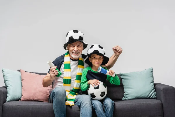 Homme excité montrant geste de victoire tout en regardant le championnat de football avec petit-fils isolé sur gris — Photo de stock