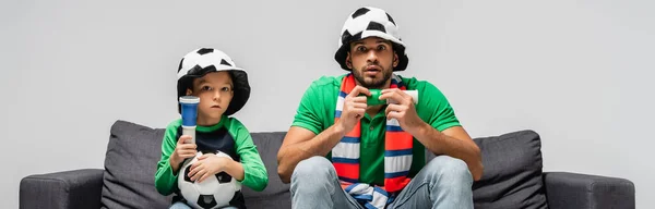 Preocupado padre e hijo en abanicos viendo campeonato de fútbol aislado en gris, bandera - foto de stock