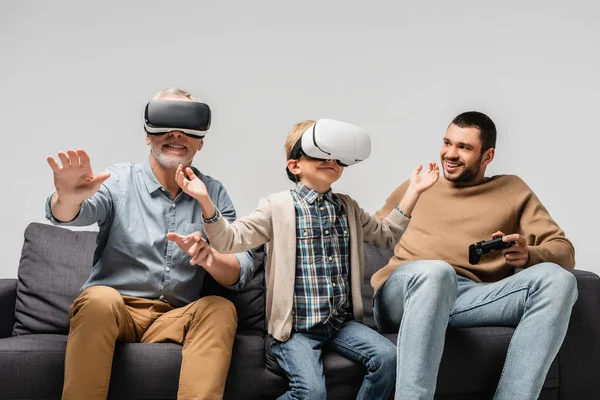 KIEW, UKRAINE - 17. NOVEMBER 2020: Fröhlicher Mann blickt Sohn und Vater gestikulierend in vr-Headsets isoliert auf grau — Stockfoto