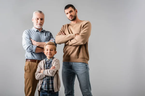 Hombres felices y niño de pie con los brazos cruzados mientras mira a la cámara aislada en gris - foto de stock