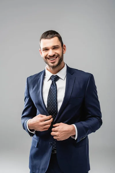 Веселий бізнесмен в офіційному одязі посміхається на камеру ізольовано на сірому — стокове фото