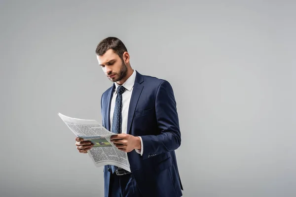 Thoughtful businessman in formal wear reading newspaper isolated on grey — Stock Photo