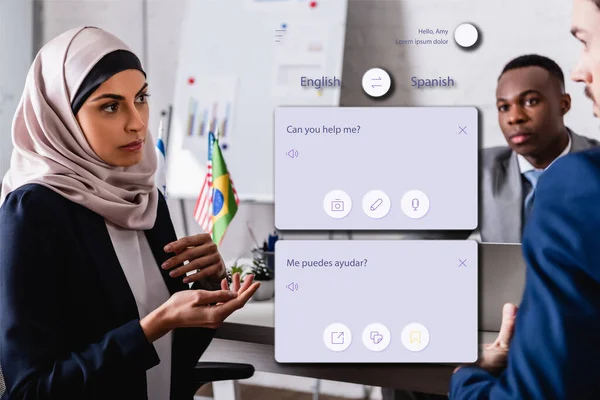 Arabian businesswoman gesturing while talking to interpreter near african american business partner, translation application interface illustration — Stock Photo