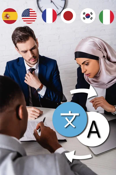 Multicultural business partners discussing contract in office, flags of different countries near icons with arrows illustration — Stock Photo