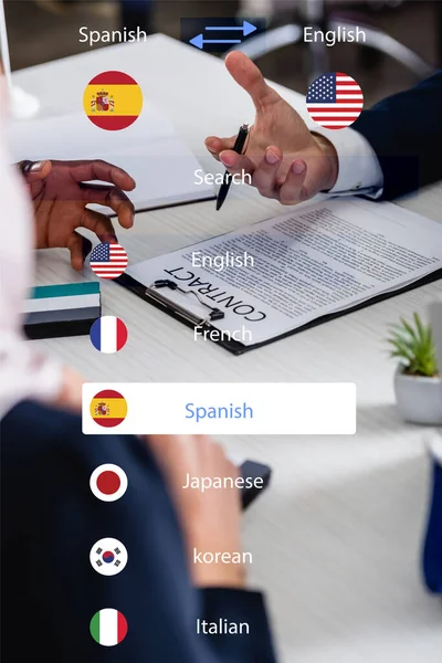 Cropped view of multicultural business partners near contract, blurred foreground, translation app interface illustration — Stock Photo