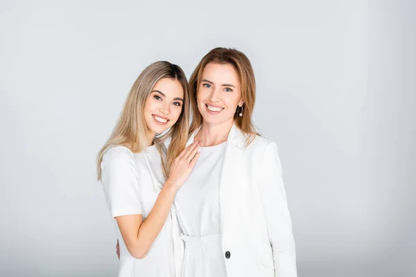 Happy mother and daughter smiling while looking at camera on grey, generation of women — Stock Photo