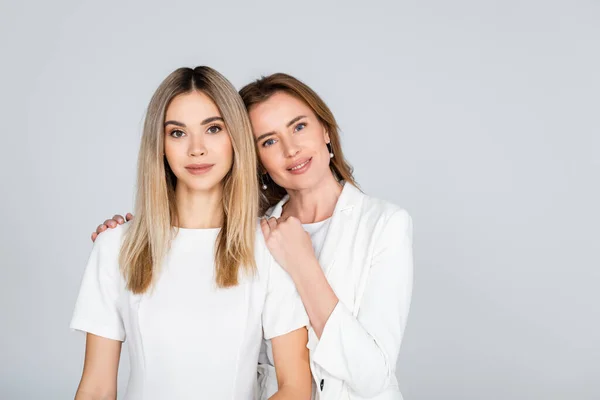 Happy mother hugging young daughter isolated on grey — Stock Photo