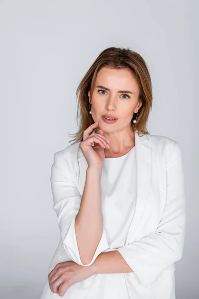 Woman in white outfit looking at camera isolated on grey — Stock Photo