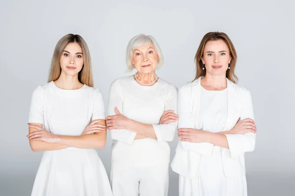 Tre generazioni di donne in piedi con le braccia incrociate isolate sul grigio — Foto stock