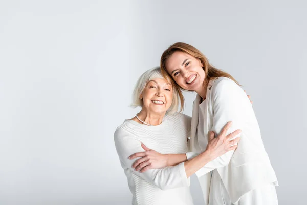 Madre mayor abrazo con feliz hija aislado en gris - foto de stock