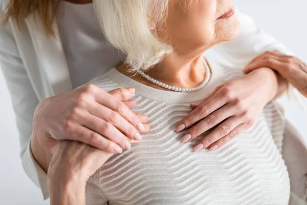 Vista ritagliata della figlia che abbraccia la madre anziana con i capelli grigi — Foto stock