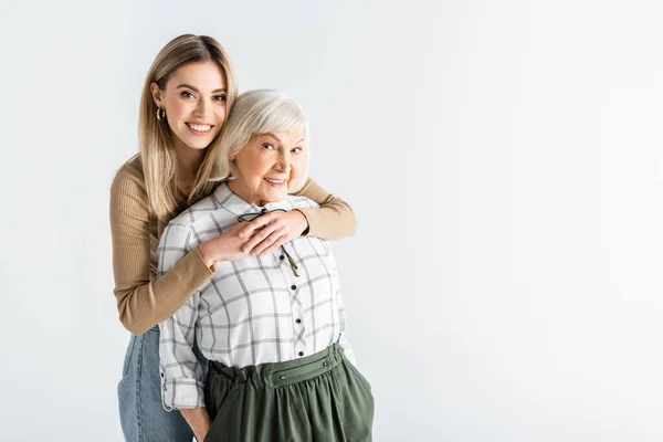 Cheerful granddaughter hugging senior granny isolated on white — Stock Photo