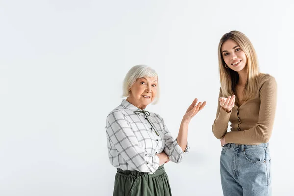 Щаслива онука і бабуся стоять і вказують руками ізольовані на білому — стокове фото