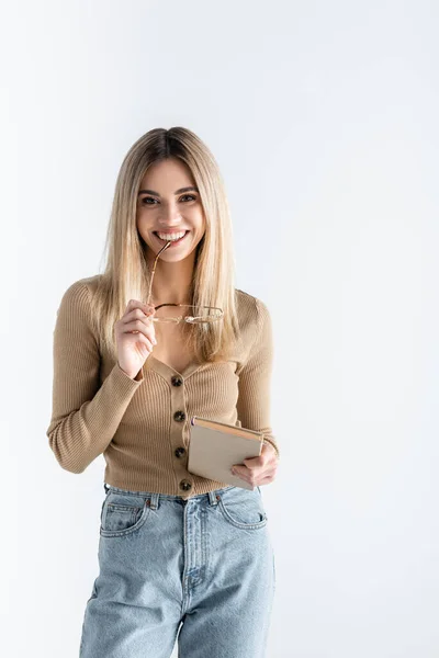 Allegra giovane donna che tiene libro e occhiali isolati su bianco — Foto stock