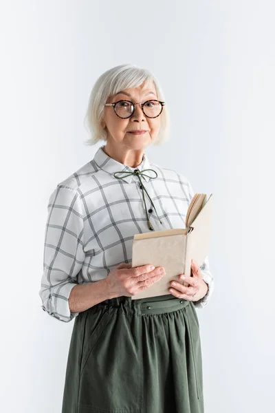 Senior woman in glasses holding book isolated on white — Stock Photo