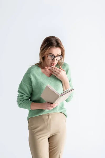 Здивована жінка в окулярах читає книгу ізольовано на білому — стокове фото