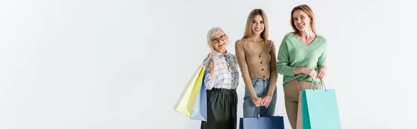 Trois générations de femmes heureuses tenant des sacs à provisions isolés sur blanc, bannière — Photo de stock