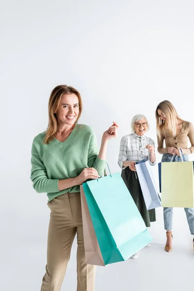 Mulher feliz com sacos de compras perto da filha e mãe sênior no fundo borrado — Fotografia de Stock