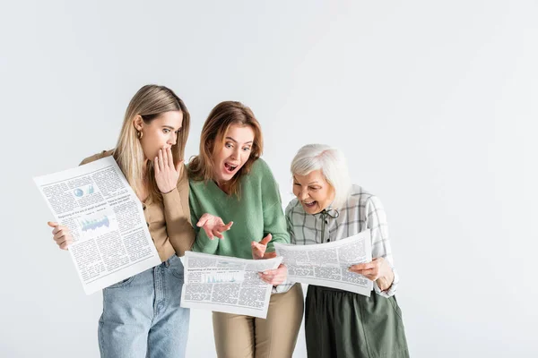 Tres generaciones de mujeres sorprendidas leyendo periódicos aislados en blanco - foto de stock
