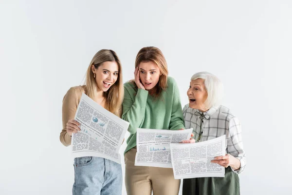Três gerações de mulheres espantadas lendo jornais isolados em branco — Fotografia de Stock